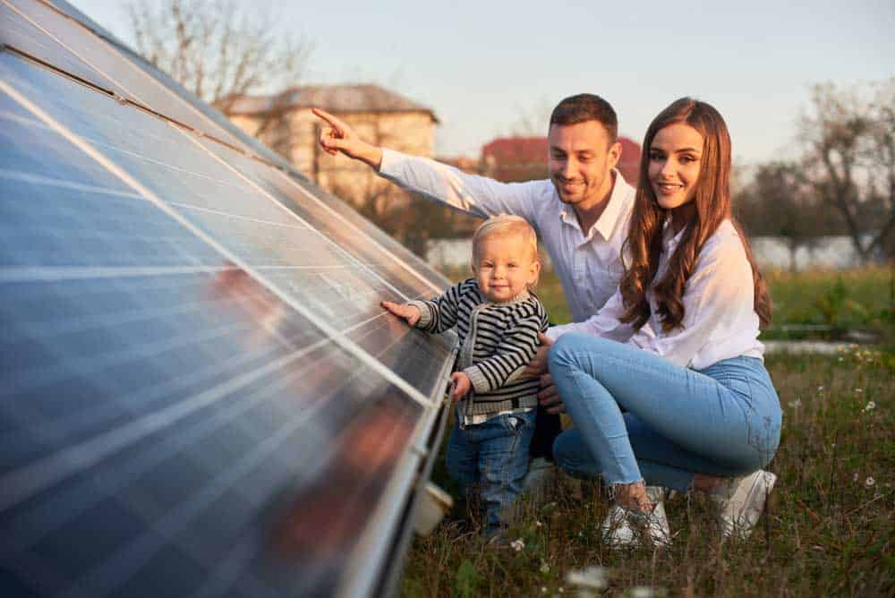 A family posing next to a ground-mounted solar assembly