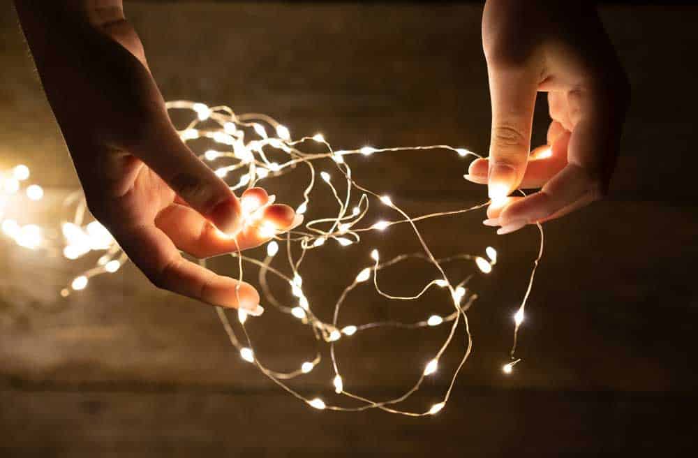 A young woman holding fairy lights in her hands