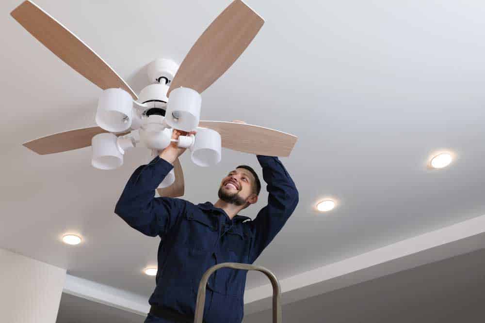 A happy electrician repairing ceiling lamps